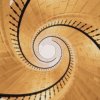 Vue du dessus d’un escalier en colimaçon en bois formant une spirale lumineuse et harmonieuse.