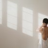 Femme debout dans une pièce lumineuse, prenant un moment pour ralentir et se reconnecter à elle-même.