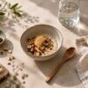 Bol de porridge aux fruits et aux noisettes sur une table en pierre.